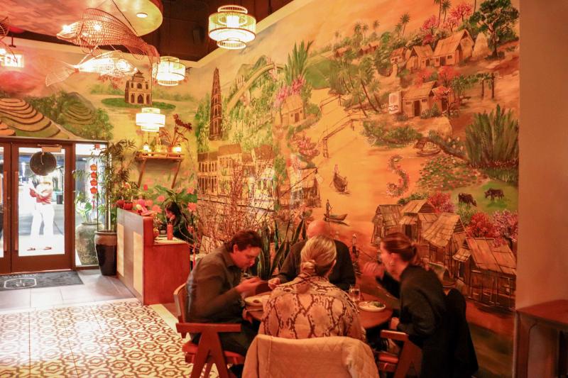 entrance of Bao Toan with mural of Vietnam on wall next to ladies eating dinner