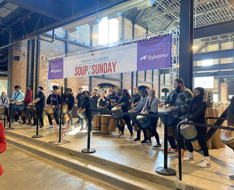 young adults play instruments in front of Soup Sunday banner