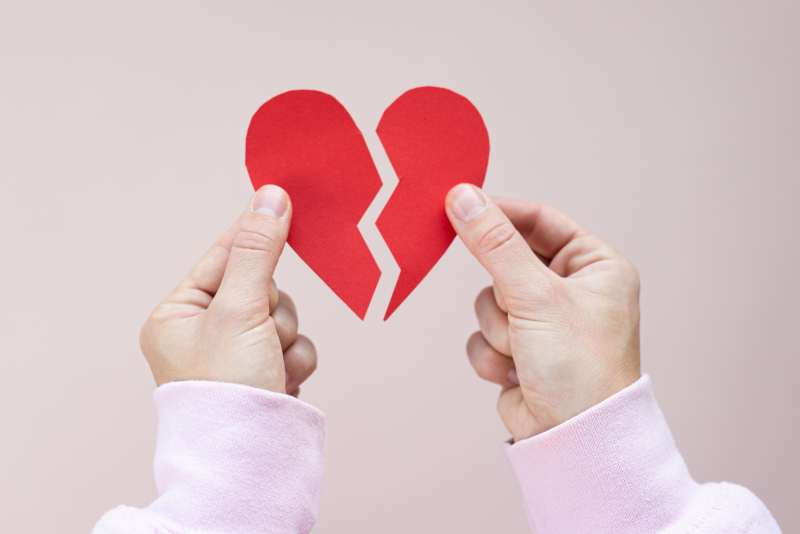 hands holding up two sides of a broken heart