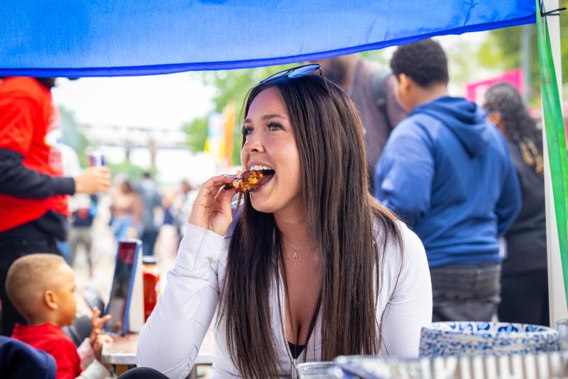 woman poses for photo eating hot wing
