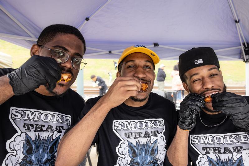three men pose for photo eating hot wings