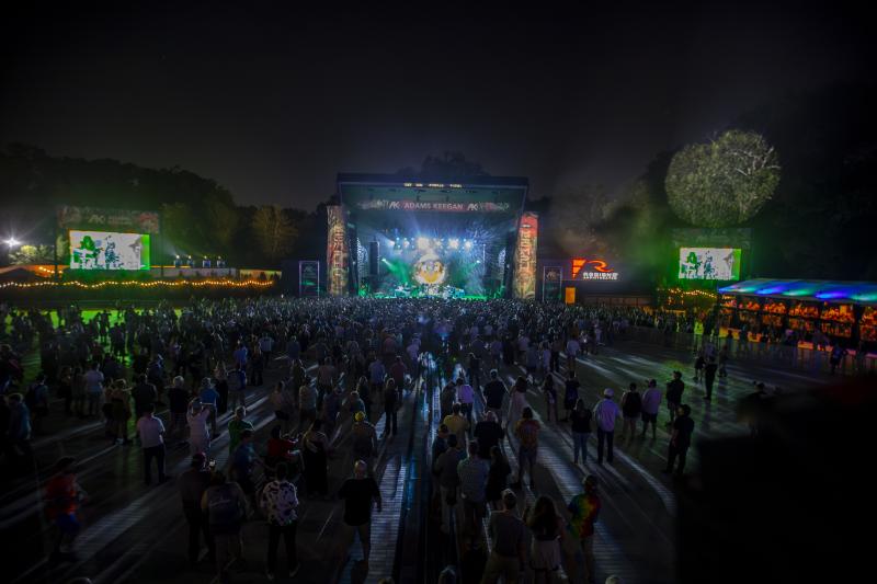 widest from far back showing music stage lit up at night and large crowd
