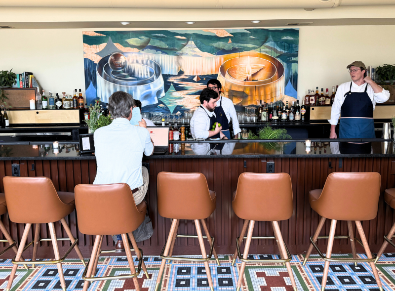 Man sits at bar at Bar Liminia while bartenders work behind it