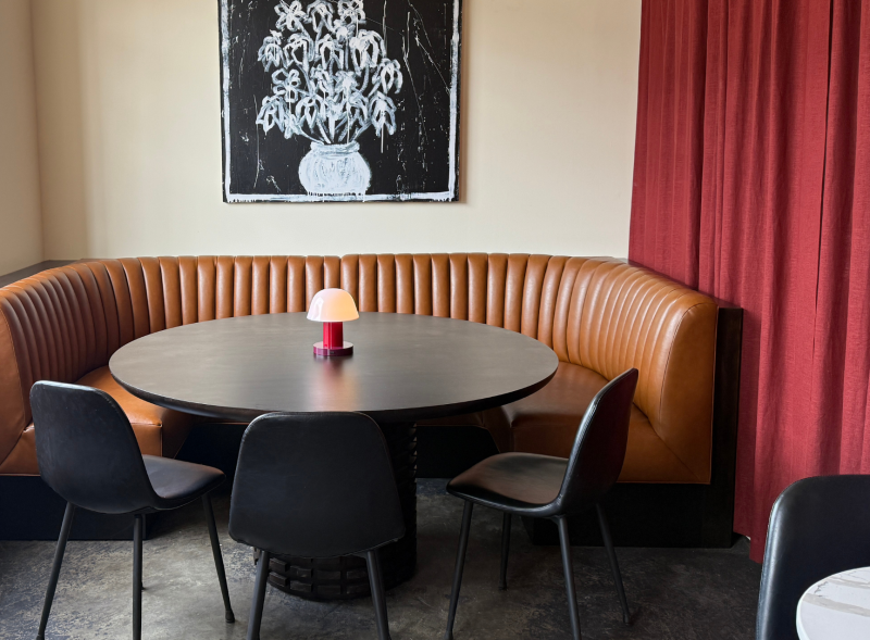 large brown corner booth with black table and chairs