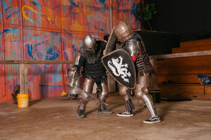 two people in knight armor battle with swords and shields