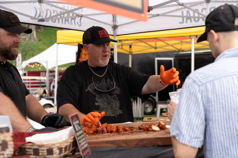 man hands out barbecue samples at smokeslam