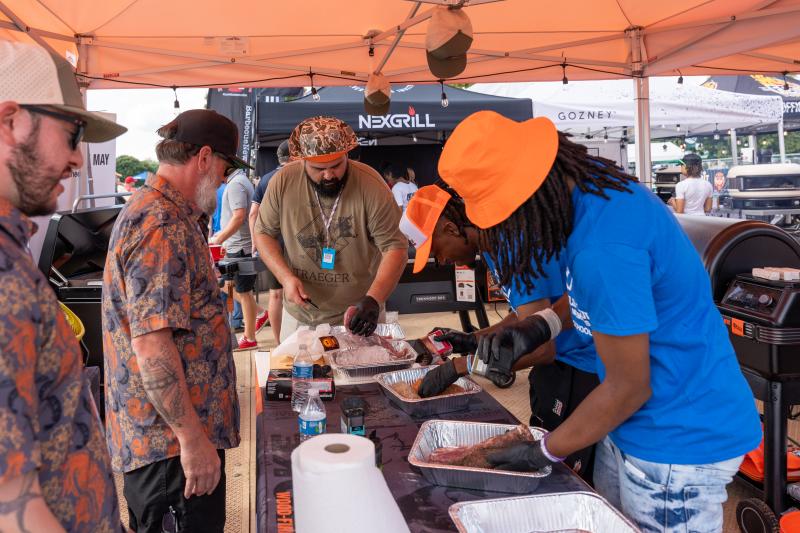 men prepare bbq for guests at world championship barbecue cooking contest