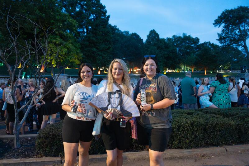three women pose for photo with elvis memorabilia at candlelight vigil at Graceland