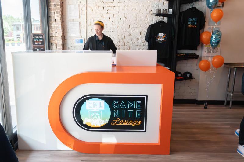 woman stands behind game nite lounge front desk