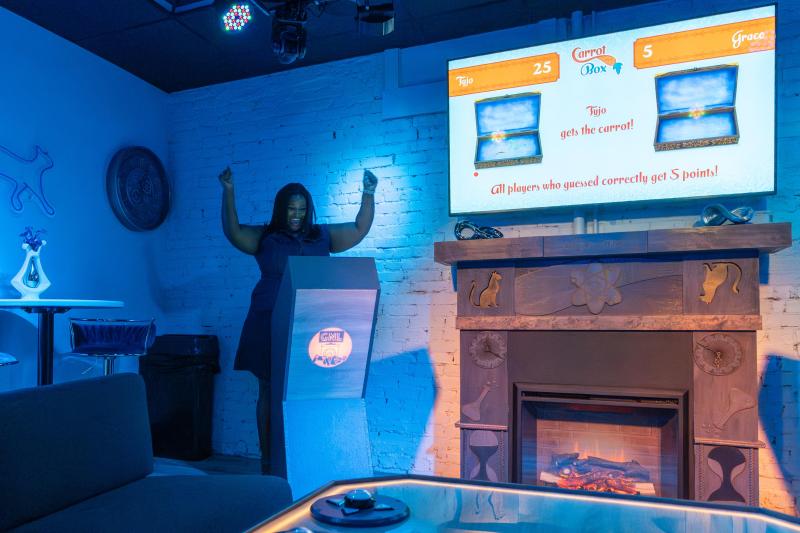 woman celebrates winning game behind game show stand