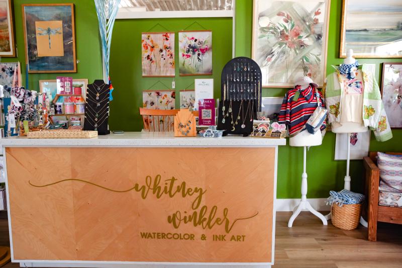 check out desk with business name and green wall filled with paintings