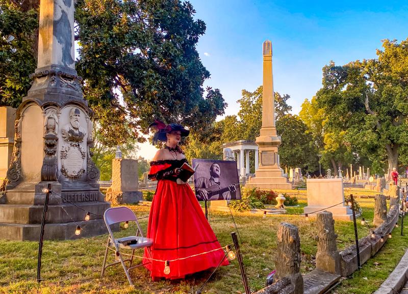 A storyteller dressed in period garb telling stories on a tour of Elmwood Cemetery.