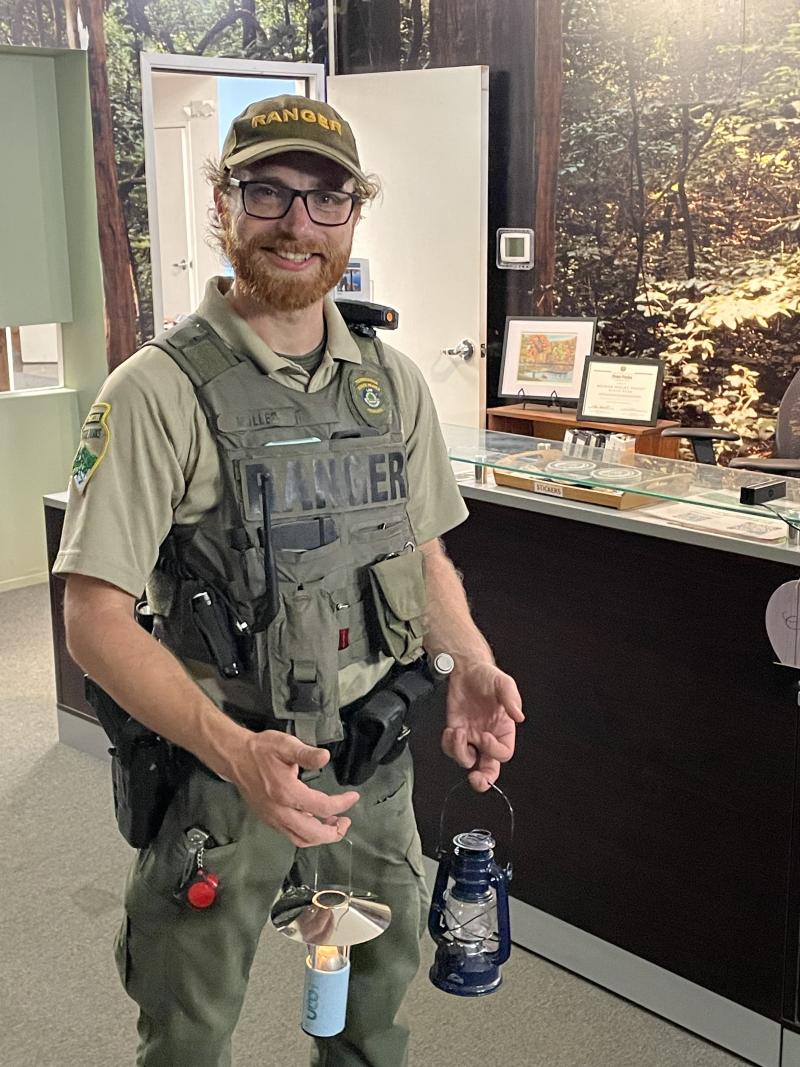 ranger holds lanterns in hands and smiles for photo