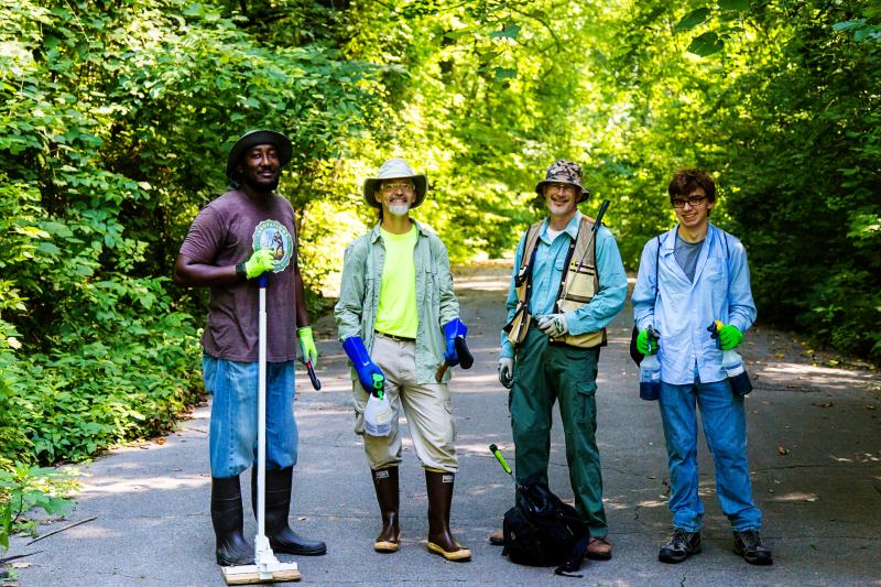 four male employees stand in middle of trail smiling for photo