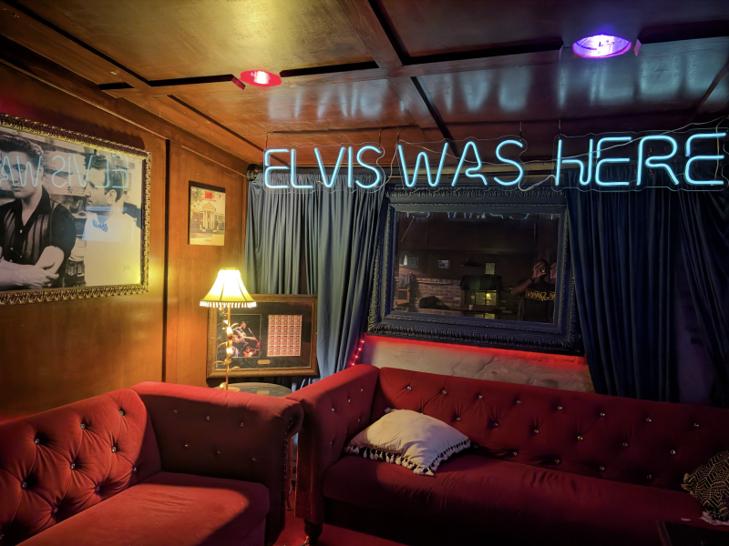 red couches in corner seating area with &quot;elvis was here&quot; neon sign next to a photo of elvis with jerry