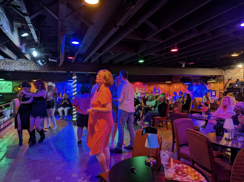 people dancing on the dance floor and sitting at tables