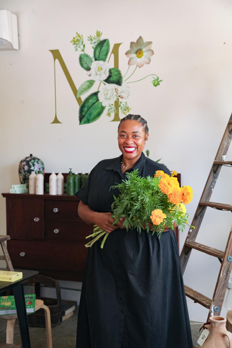 the band wilding owner smiles for photo holding yellow flowers