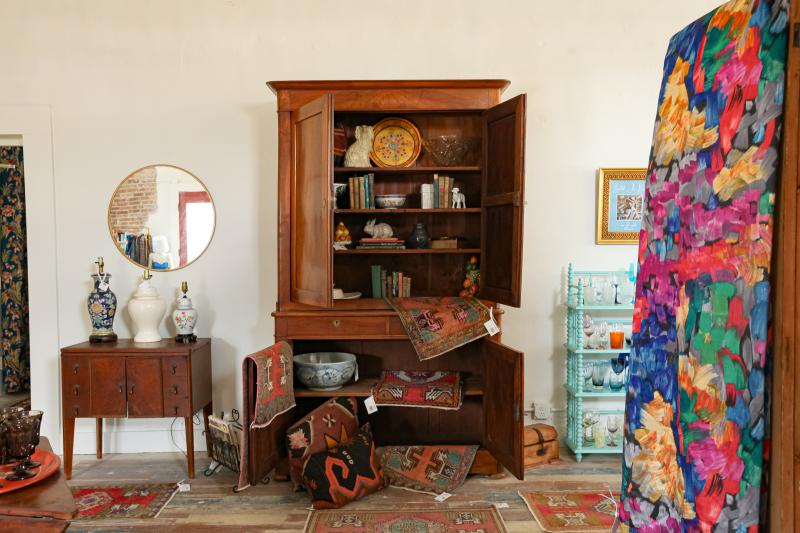 a large wooden armoire with a wooden nightstand and colorful knick knacks placed around it
