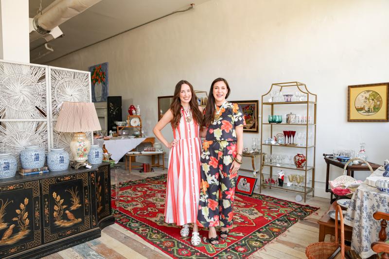 Two women standing next to each other surrounded by antiques
