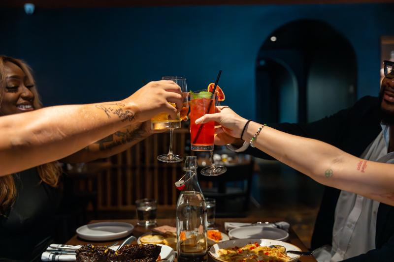 Friends raising glasses, we just see arms extended with glasses cheersing