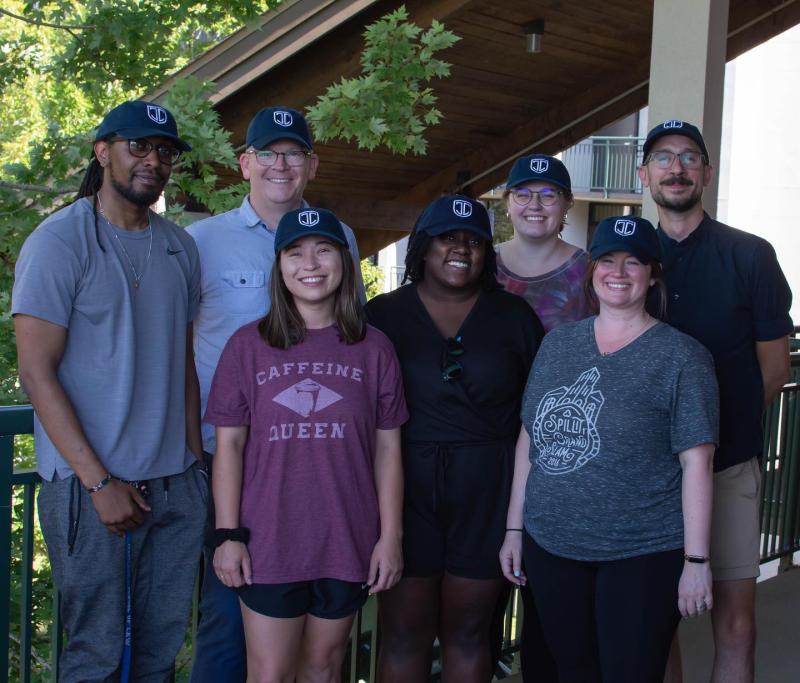 a group of people standing together smiling wearing matching navy baseball caps