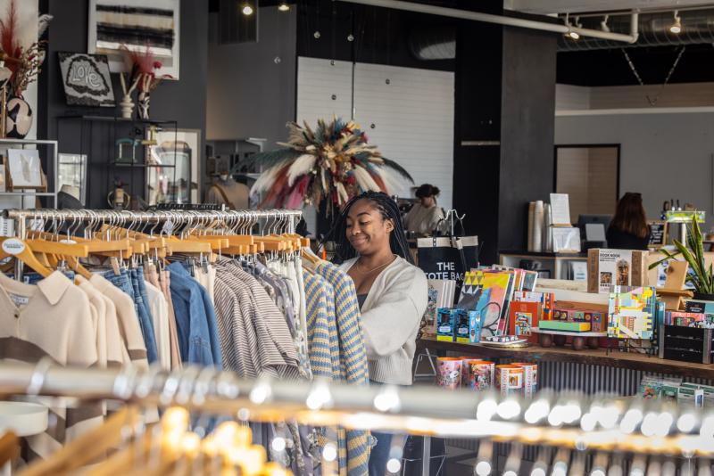 Girl shopping and sorting through clothing racks at a store