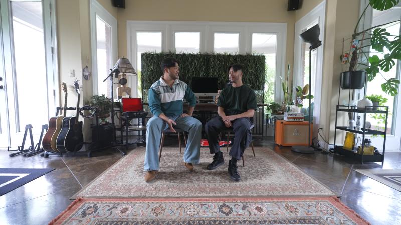 two filipino men sitting next to each other, facing one another as they talk