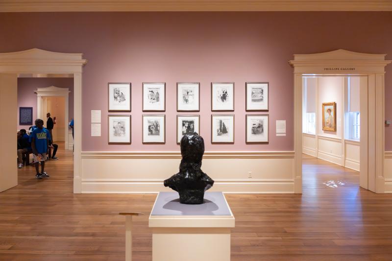 bust statue sits on display in middle of room with photos on wall