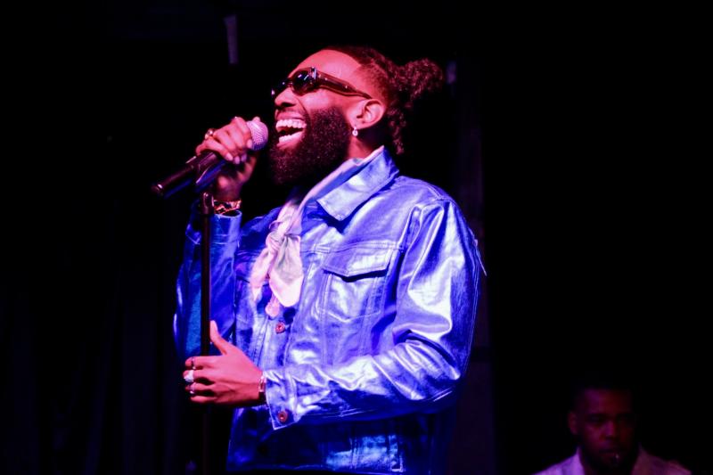 black man singing in a metallic purple jacket