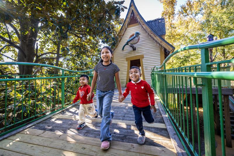 three kids holding hands, running, smiling having fun outdoors