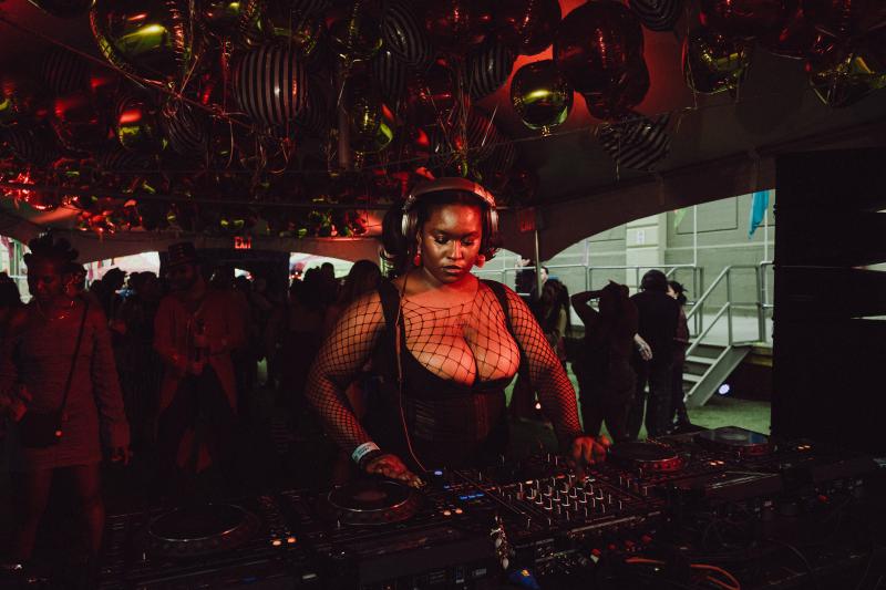 African American Woman Djing, wearing headphones with black fishnext top and black corset