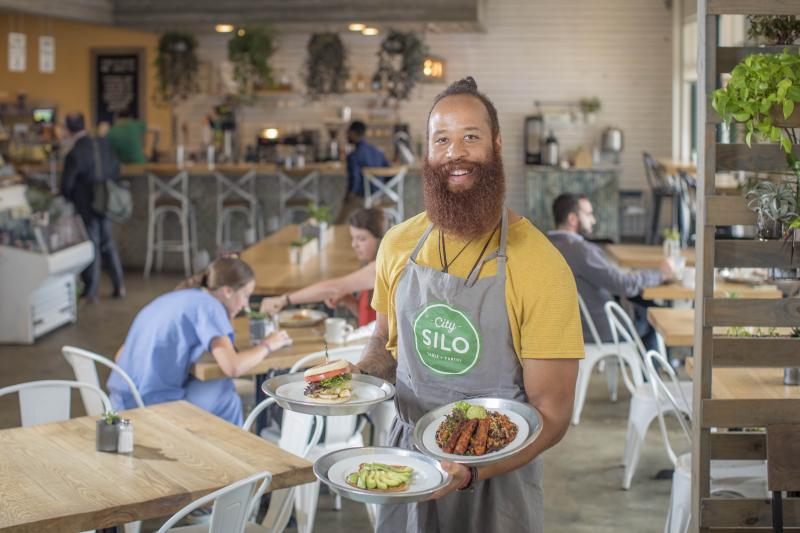 City Silo employee poses with various dishes.