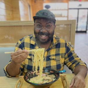 photo of Wesley smiling and holding up ramen noodles