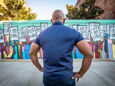 man facing the I AM Man Mural 