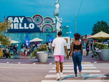 couple holds hand walking across the street in edge district