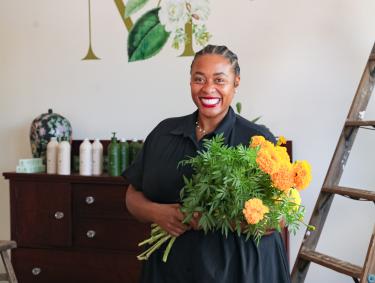 the band wilding owner smiles for photo holding yellow flowers