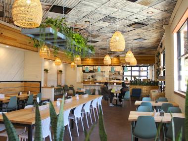 restaurant interior with warm lighting, long tables, hanging woven lamps