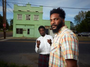 two men standing in front of historic green buildling