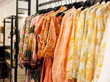 row of colorful warm colored blouses at boutique