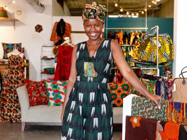owner of mbabazi shop posing in a green and black dress in the shop