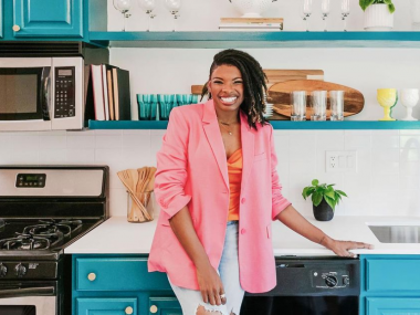 woman in colorful kitchen wearing pink blazer