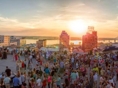 Crowds gathered at a Rooftop Party at The Peabody Memphis as the sun sets over the Mississippi River.