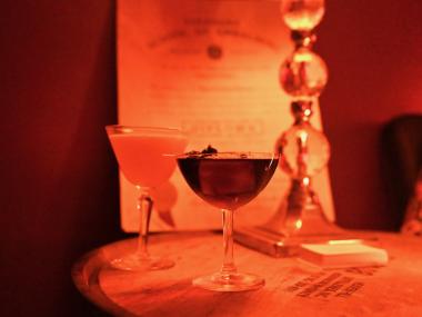 two craft cocktails on an antique table in soft sepia lighting