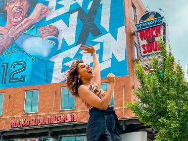 A traveler stands in front of a colorful mural outside the Rock 'n' Soul Museum.