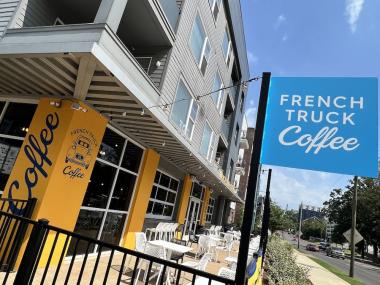 patio of coffee shop, exterior walls are bright yellow, a blue sign says French Truck Coffee