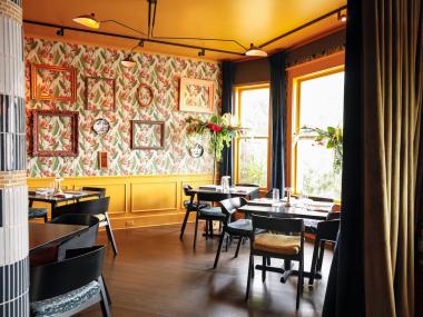 warmly lit dining room with floral wallpaper and frame collage and tables