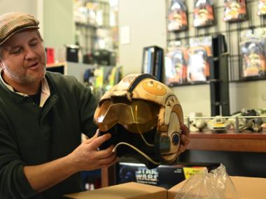 shop owner holding a vintage Star Wars character helmet