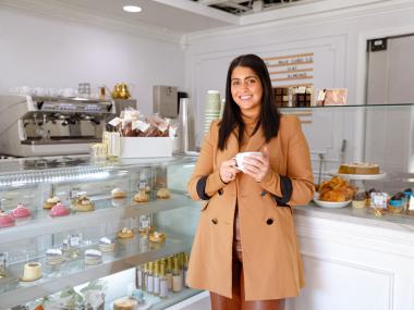 Owner of 17 Berkshire stands in front of treats display case smiling for photo