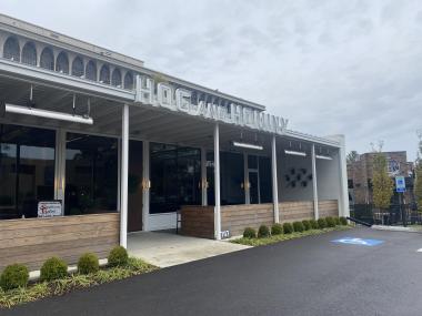 Exterior photo of Hog and Hominy from parking lot. name of restaurant sits on roof above entrance