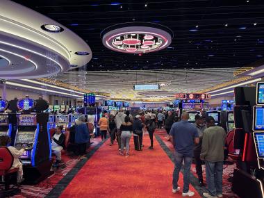 walkway of casino floor red carpet with slot machines on both sides and an illuminated ceiling